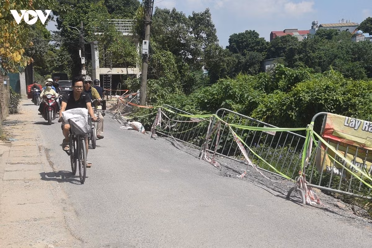 Một đoạn đường bị sụt lún mép đường bị khoét sâu, tạo khoảng trống lớn giữa phần mặt đường còn lại và bờ sông