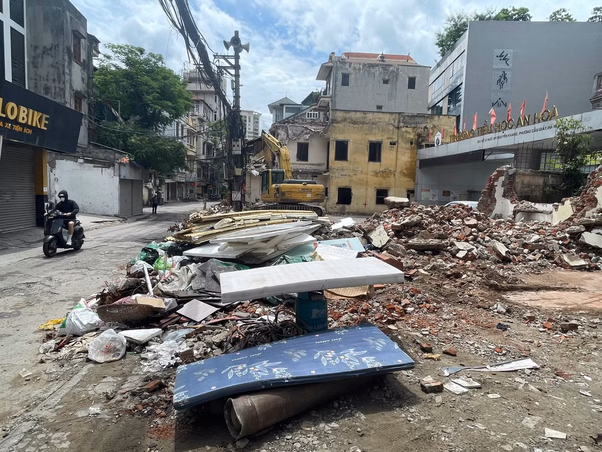 Những ngày đầu tháng 7, ngõ 381 Nguyễn Khang không còn là hình ảnh quen thuộc của một con ngõ chật hẹp ken đặc phương tiện. Thay vào đó là những căn nhà đang được tháo dỡ, tường gạch đổ xuống, máy xúc hoạt động liên tục và hàng rào công trường được dựng lên dọc tuyến.