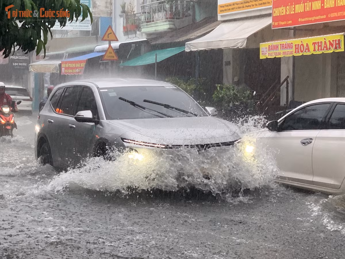 Ô tô rẽ "sóng nước" trên đường ngập trong chiều cuối tuần sau cơn mưa lớn ở TP HCM.