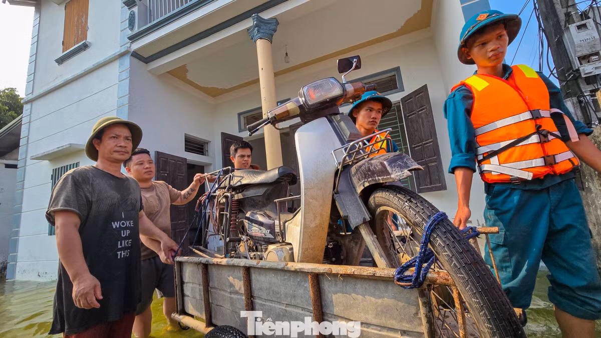 Lực lượng tại chỗ hỗ trợ người dân đưa xe máy và tài sản ra khỏi khu vực ngập sâu.
