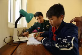 Chiến sỹ đồn Biên phòng Pa Thơm, tỉnh Điện Biên hướng dẫn cháu Quàng Trung Thành học bài sau giờ lên lớp. Ảnh: Phan Tuấn Anh/TTXVN