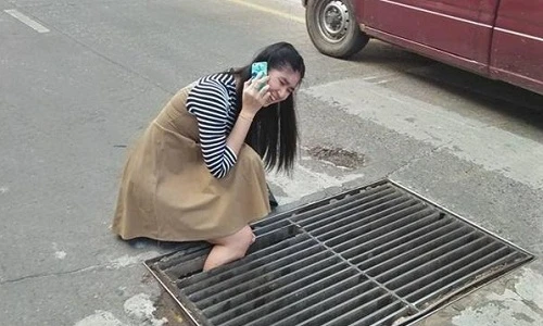 Đi đường “cắm mặt vào điện thoại”, gái xinh bị thụt chân xuống cống