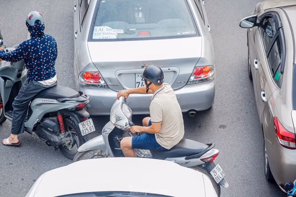 Xe máy luồn lách giữa hai ô tô.