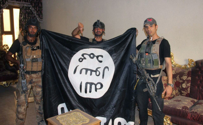 Lính Iraq chụp cùng một lá cờ đen IS bị tháo dỡ hôm 19/6.