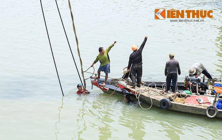 Từ sáng sớm, hàng chục thợ lặn đã lặn xuống đáy sông sâu 14 mét để móc dây cáp vào thân tàu.