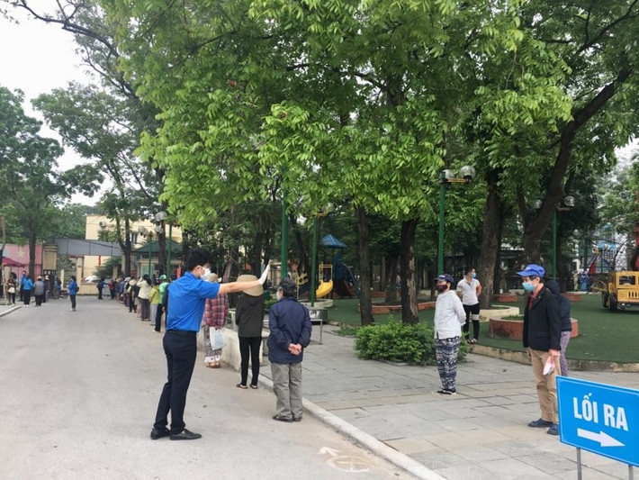 Tình nguyện viên hướng dẫn người dân đến nhận gạo xếp hàng để tránh tình trạng chen lấn mất an toàn trong việc phòng dịch COVID-19.