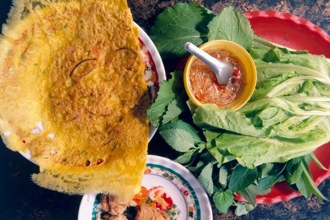 Bánh xèo: Những chiếc bánh to, ngon mà rẻ này có phần vỏ bột giòn, nhân tôm, thịt, giá và trứng. Món bánh dân dã này được cuốn trong bánh tráng với rau thơm và chấm nước mắm cay. Ảnh: Roughguides.