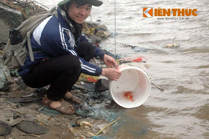 Một bạn sinh viên tình nguyện ngồi ở bờ sông phía dưới cầu Long Biên sẽ cầm chiếc xô...