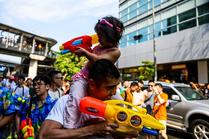 Một bé gái phun nước vào người đi đường khi ngồi trên vai bố mình. Trong thông điệp Songkran, Thủ tướng Thái Lan Prayut Chan-o-cha đã kêu gọi đoàn kết dân tộc nhằm tạo ra một bầu không khí hòa bình để đất nước có thể tiến tới dân chủ.