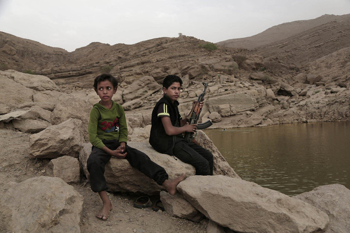 Một cậu bé cầm súng bên con đập ở thành phố Marib, Yemen. Nhiều người chú ý tới thảm họa nhân đạo do nạn đói gây ra trong cuộc nội chiến, nhưng những chiến binh trẻ em cũng là một phần đau thương của cuộc chiến này. Ảnh: AP.