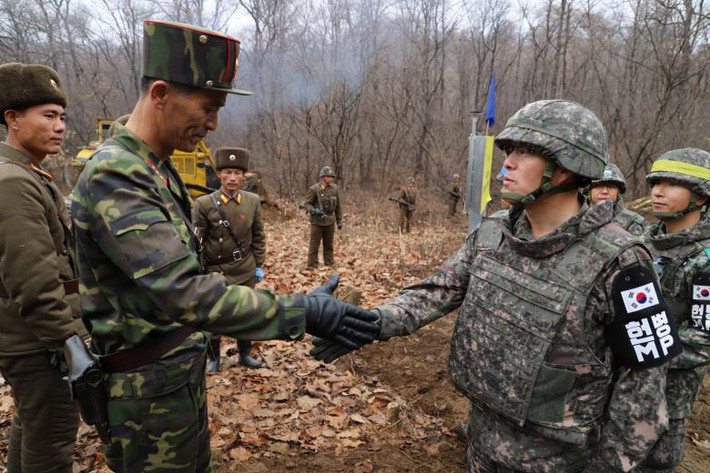 Hình ảnh một sĩ quan quân đội Hàn Quốc (phải) và một sĩ quan quân đội Triều Tiên bắt tay nhau trong một chiến dịch để kết nối lại một con đường xuyên qua khu vực Khu phi quân sự (DMZ) ngăn cách hai miền Triều Tiên từ những năm 1950 co tới nay. Ảnh: Reuters.
