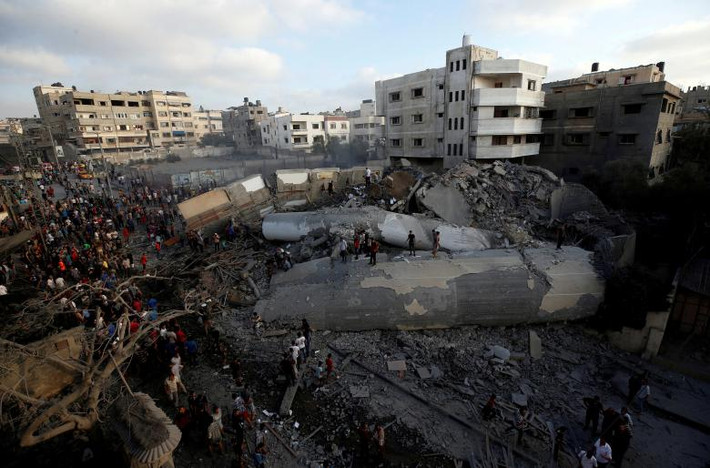 Người dân Palestine tập trung quanh một tòa nhà sau khi nó bị máy bay Israel ném bom phá hủy hoàn toàn, tại thành phố Gaza, vào ngày 9/8/2018. Ảnh: Reuters.