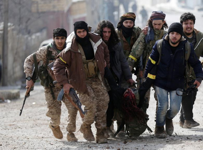 Một nhóm các chiến binh Quân đội tự do Syria được Thổ Nhĩ Kỳ hậu thuẫn mang theo "đồng nghiệp" bị thương của chúng ở Rajo, Syria, bức ảnh này được chụp vào tháng 3 năm nay.