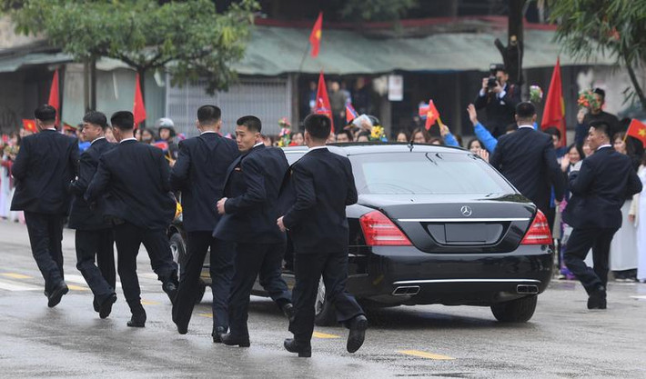 Cận vệ Triều Tiên chạy bên chiếc xe hơi chở Chủ tịch Kim Jong-un. Triều Tiên đã tự chở những chiếc xe hơi này sang Việt Nam bằng tàu hỏa. Nguồn ảnh: Reuters.