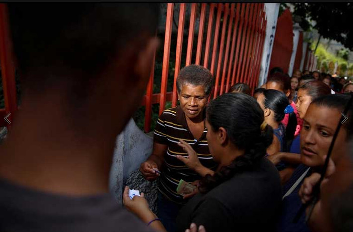 Người phụ nữ nhận tờ số thứ tự để mua hàng trong khu chợ. Ảnh Reuters