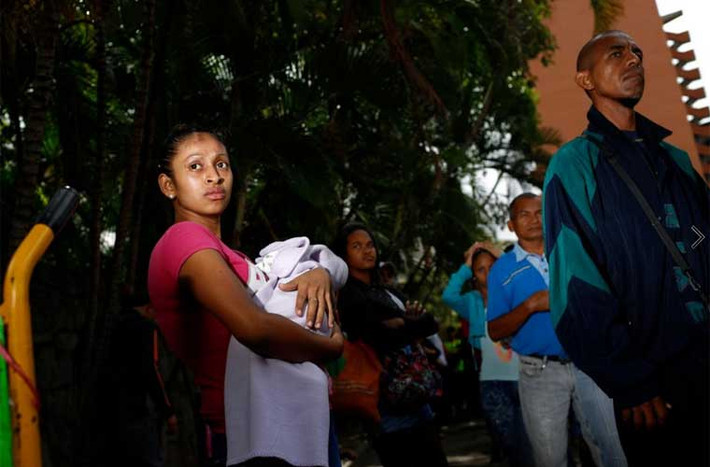Bà mẹ trẻ bế theo đứa con nhỏ sơ sinh cũng đi chờ mua hàng trong một siêu thị. Ảnh Reuters