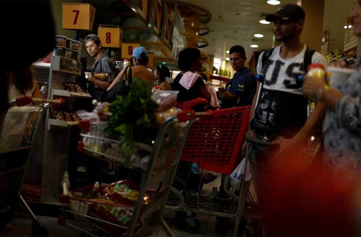 Mọi người chờ thanh toán tiền tại quầy thu ngân của một siêu thị. Ảnh Reuters