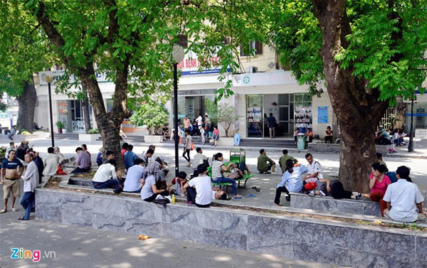 Trưa ngày 27/5, trong khuôn viên bệnh viện Bạch Mai (Hà Nội) rất đông người nhà bệnh nhân vạ vật dưới bóng cây, bên ghế đá nằm nghỉ. Thời tiết nắng nóng lên tới 39 độ C khiến ai cũng mệt mỏi và khó chịu.