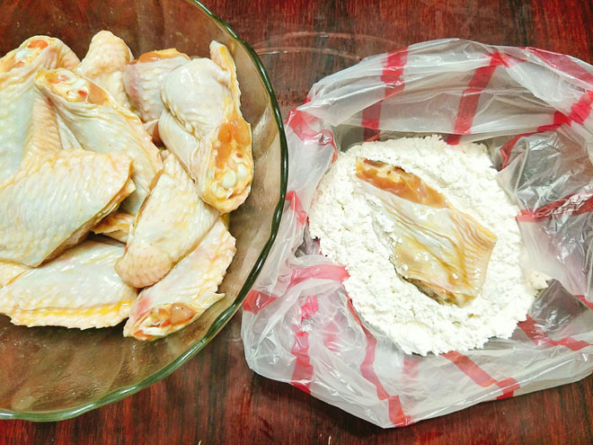 Bước 4: Cho bột mì, bột nở vào túi nilon sạch sau đó trộn đều, tiếp theo cho cánh gà đã ướp gia vị vào cùng rồi túm chặt túi, xóc đều cho cánh gà bám đều 1 lớp bột bên ngoài.