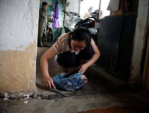 Chị Vân (38 tuổi, Tân Mai, Hoàng Mai, Hà Nội) đang trát lại phần rãnh nứt ở tầng 5. Chị chia sẻ: "Nhà tôi ở tầng cao nhất nên cũng lo sợ nhất. Cứ lúc mưa gió dột hết nước và thỉnh thoảng trần nhà gạch đá vụn vỡ rơi liên tục. Tôi hoang mang và lo sợ lắm nhưng không biết làm thế nào, đành sống chung với lũ thôi"