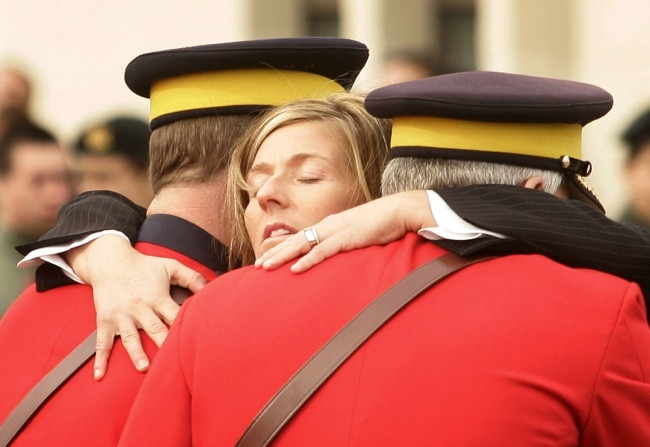 Kelly Johnston, vợ của một sĩ quan Cảnh sát Hoàng gia Canada, được đỡ bởi hai sĩ quan khi bà gục ngã trong đám tang của chồng bà.