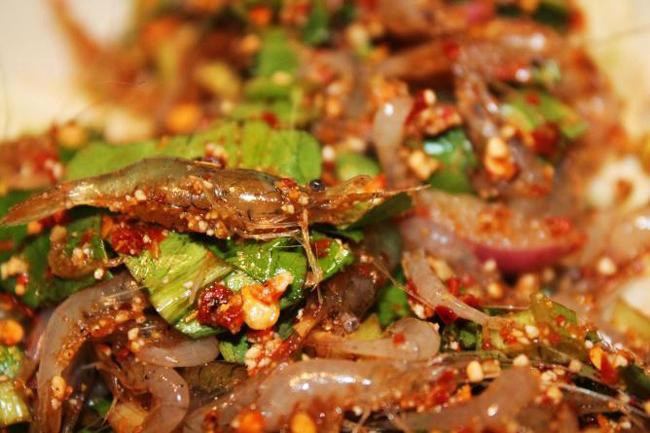 1. Goongten Món ăn kinh dị này còn có tên là tôm nhảy múa. Thực khách sẽ ăn nó khi nó vẫn còn sống, búng tanh tách trong miệng. Những con tôm sống được trộn với gia vị Thái, ớt khô, hành tím cắt nhỏ sau đó rưới thêm một chút nước cốt chanh.
