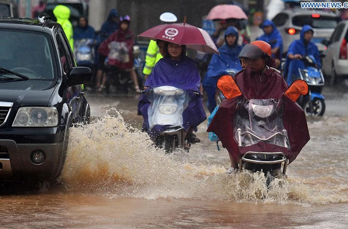 Mọi người di chuyển phương tiện trên con đường ngập nước lênh láng.