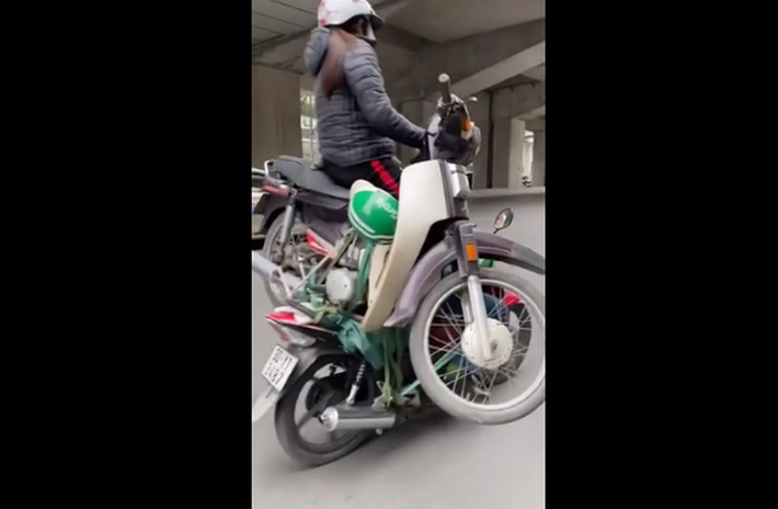 Người phụ nữ ngồi vắt vẻo trên xe không màng tới nguy cơ tai nạn có thể xảy đến trong tích tắc. Ảnh: Tổng hợp
