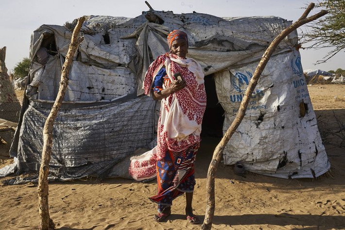 Một ngừoi phụ nữ Nigeria trước căn nhà tồi tàn của mình với chiếc điện thoại thông minh trên tay. Ảnh: Theatlantic.