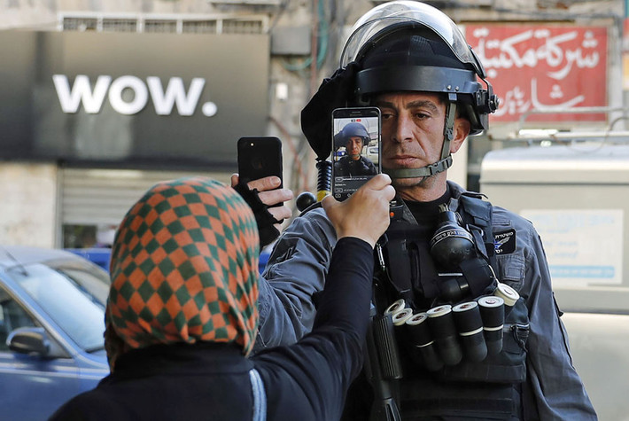 Một phụ nữ Palestine ghi hình một nhân viên nan ninh của Israel trong khi người nhân viên an ninh cũng làm điều tương tự với bà. Hình ảnh được chụp trên đường phố Jerusalem. Ảnh: Theatlantic.