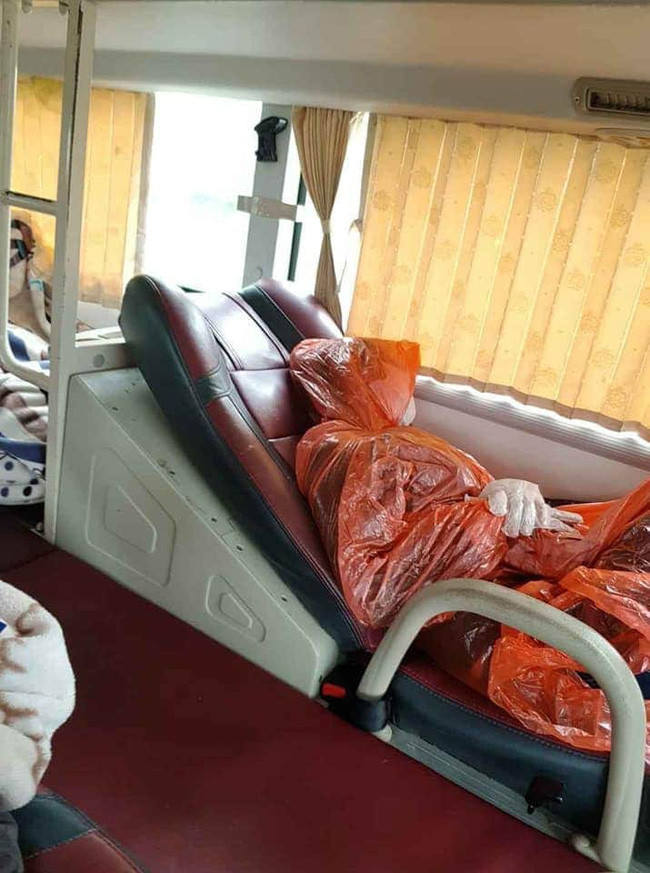 Một vị khách trùm áo mưa kín mít nằm trên xe khách.