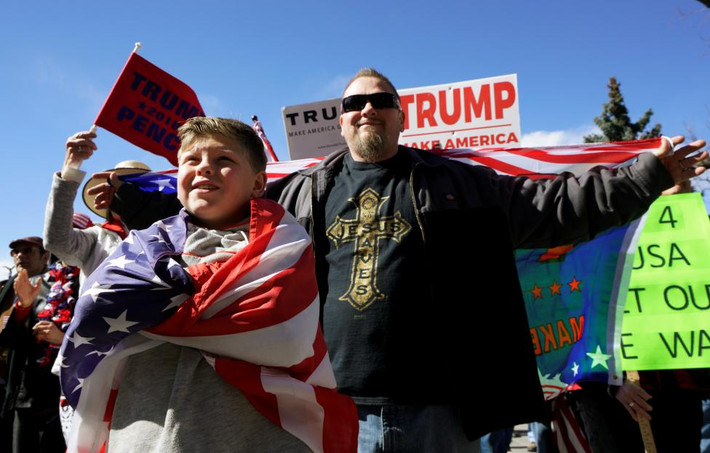 Bé trai cùng bố tham gia diễu hành ủng hộ tân Tổng thống Trump. Ảnh Reuters