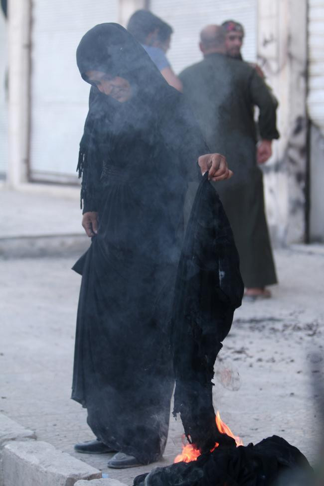 Cô gái không ngần ngại châm lửa đốt khăn trùm đầu niqab ở thị trấn Syria mới được giải phóng. Việc để râu quai nón hay mặc quần áo trùm kín mít là hai quy định mà bọn phiến quân IS đặt ra khi chúng kiểm soát nơi này từ tháng 1/2014.