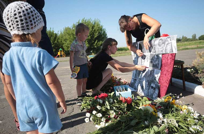 Hai năm sau thảm kịch MH17, người dân Ukraine và thân quyến của 298 nạn nhân xấu số đã tổ chức buổi tưởng niệm dành cho những nạn nhân. Ảnh: Dân làng Petropavlivka, tỉnh Donetsk, miền đông Ukraine đặt những tấm ảnh của các nạn nhân tại khu tưởng niệm tạm thời.