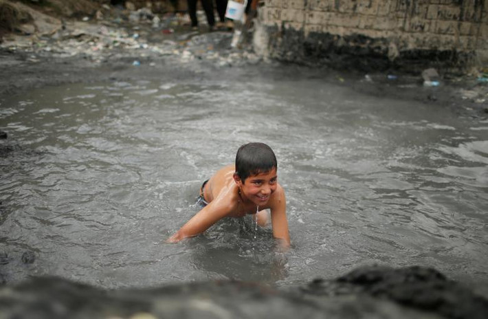 Bé trai thích thú khi được tắm ở đây. Ảnh Reuters