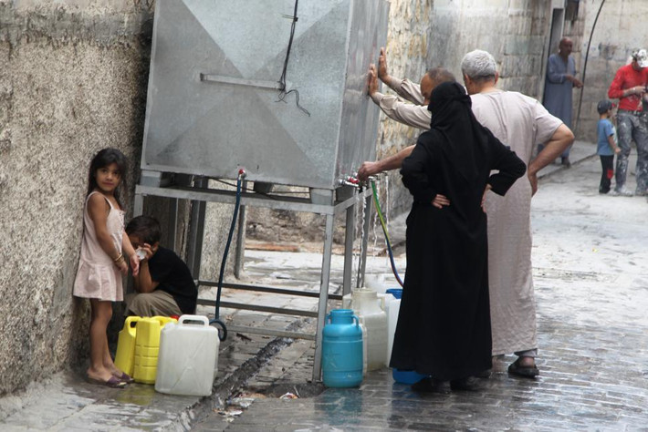 Người dân đứng chờ lấy nước ở Aleppo.