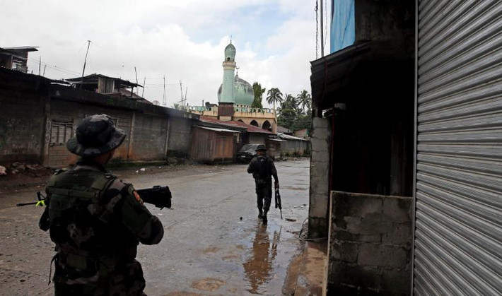 Hai binh sỹ lăm lăm cây súng trên tay đang đi tuần tra ở Marawi.