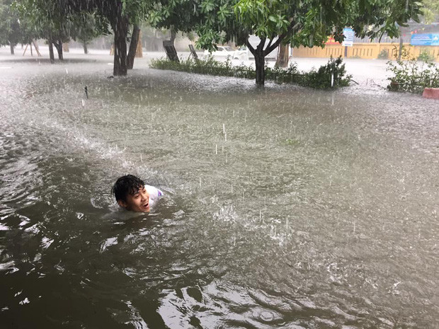 Hình ảnh một bạn sinh viên bơi lội giữa nước ngập.