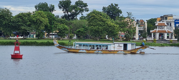 Một bên là dòng sông Hương thơ mộng với những chiếc thuyền rồng nhẹ nhàng lướt trên mặt sông.