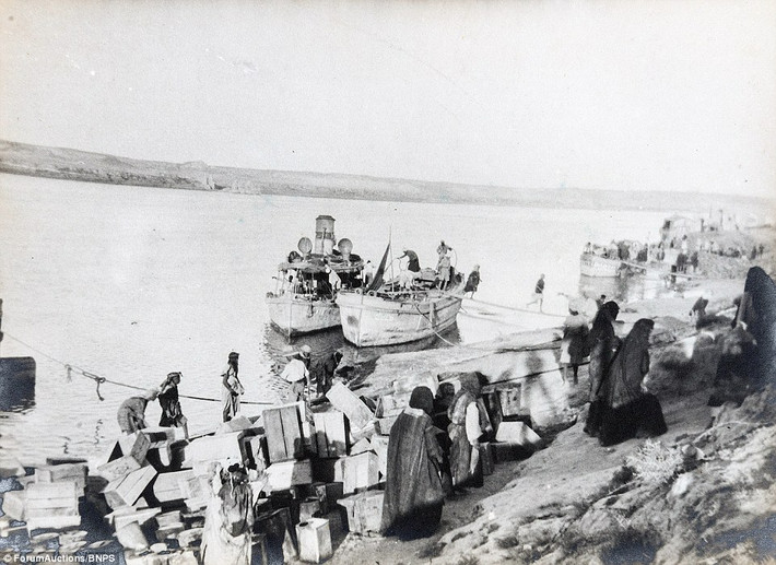 Những phụ nữ Iraq đang bỏ những thùng rỗng lên tàu bên bến sông Euphrates. Ảnh Daily Mail