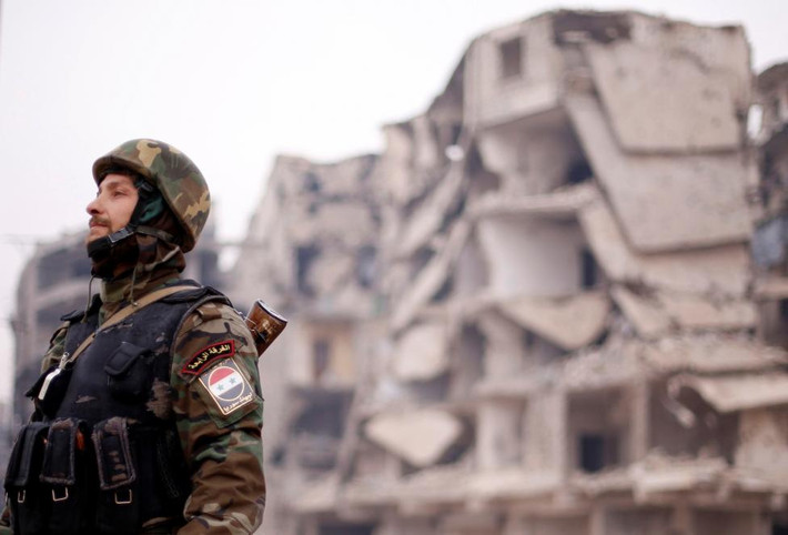 Một binh lính chính phủ Syria đứng gác gần khu đổ nát ở quận Salaheddine, Aleppo. Ảnh Reuters