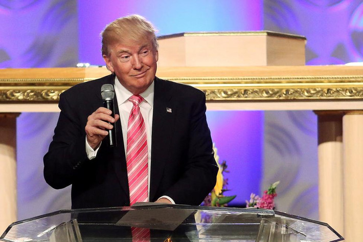 Ông Donald Trump đứng trên bục phát biểu trong nhà thờ với biểu cảm thường thấy.