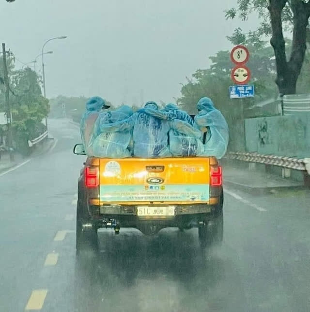 Hình ảnh những thành viên trong đội phun khử khuẩn đang ngồi ôm nhau trên thùng xe trên đường trở về trạm khử khuẩn thì gặp cơn mưa bất chợt.
