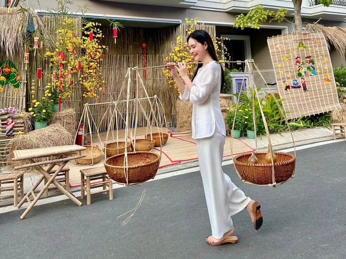 Đại gia quận 7 trang điểm nhẹ nhàng, tóc xõa, mặc áo bà ba ngồi bên bộ bàn ghế được làm từ tre khiến ai cũng thích thú.