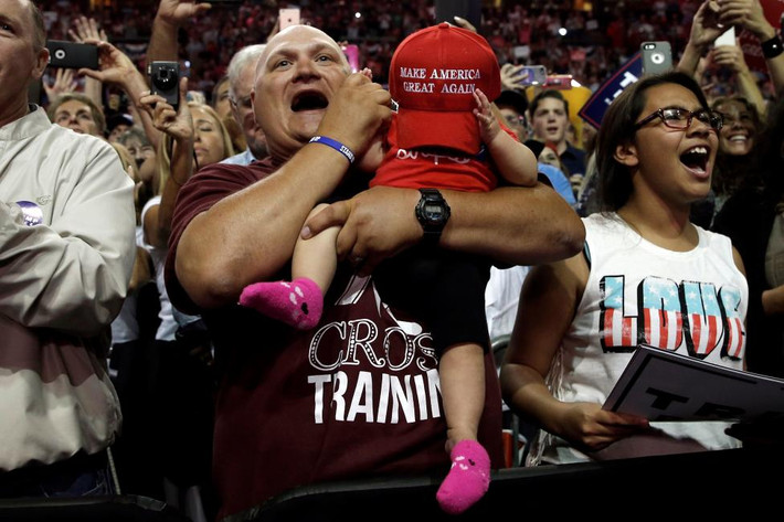 Ông bố ẵm theo con nhỏ đang cổ vũ nhiệt tình khi tới tham gia cuộc vận động tranh cử của ông Donald Trump ở Loveland, Colorado.