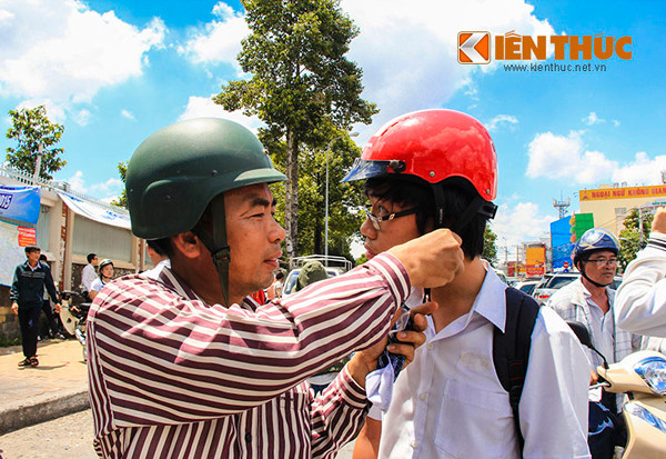 Người cha tự tay cởi dây mũ bảo hiểm cho con trai tại cụm thi trường ĐH Sư phạm Kỹ Thuật TP HCM.