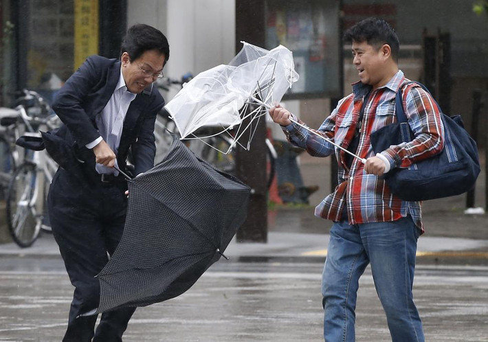 Gió tạt ô của hai người đàn ông ở Tokyo khi trận bão Wipha chuẩn bị vào Nhật Bản vào tháng 10/2013.