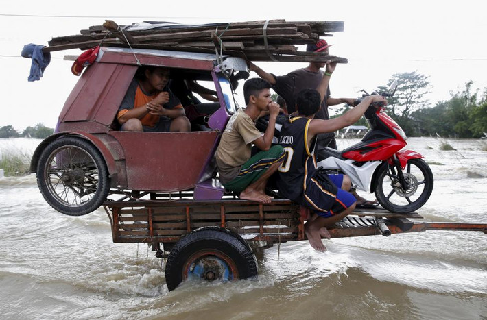 Người dân phải ngồi trên máy nông nghiệp để vượt qua đoạn đường ngập nước do bão gây ra ở miền bắc Philippines.