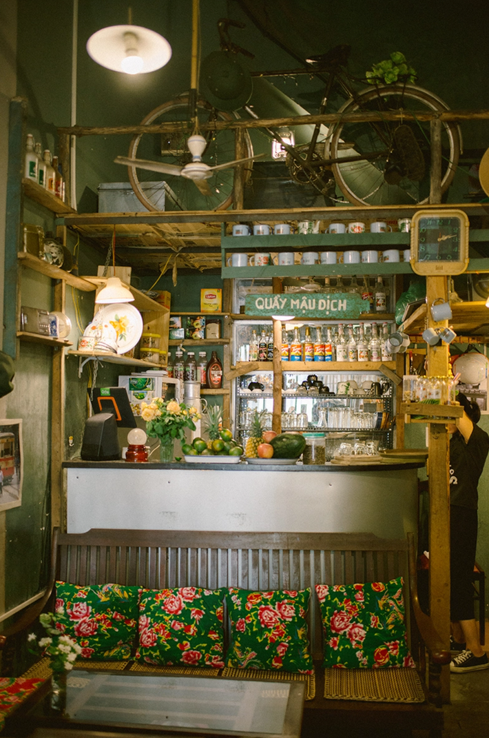 Quán cafe có diện tích khá hẹp trang trí theo tông màu vàng nhạt, bàn ghế gỗ nhỏ, đệm ghế được làm từ vỏ chăn con công, cánh cửa gỗ sờn màu, chiếc tivi huyền thoại,…Ảnh: @Baocapcafe