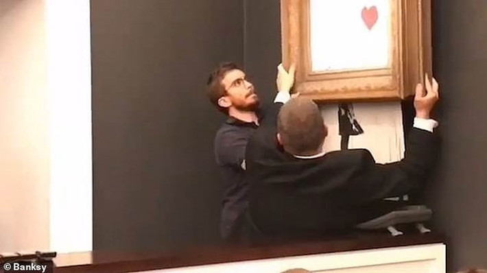 Các nhân viên của nhà bán đấu giá nhanh chóng tháo dỡ bức tranh. Banksy là một họa sỹ bí ẩn, mặc dù vậy, các tác phẩm của ông từ lâu đã được thế giới nghệ thuật đương đại phương Tây biết đến và đánh giá cao. Ảnh: Banksy.